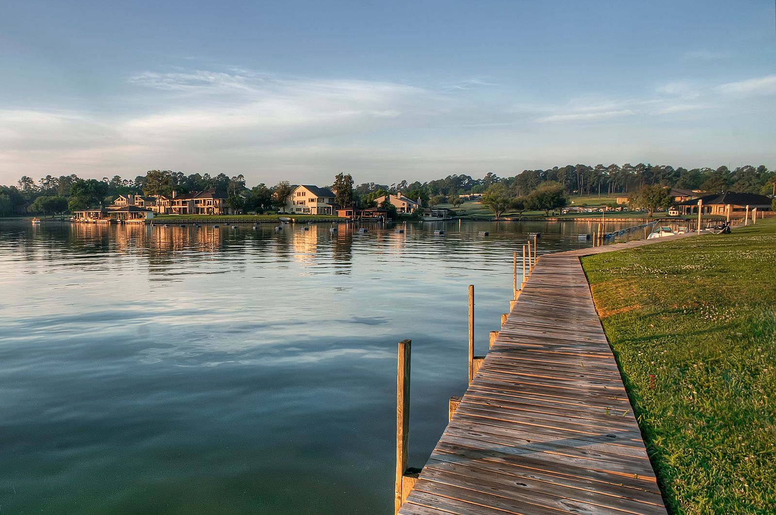 Boat dock at sunrise on Lake Conroe with waterfront homes across the water